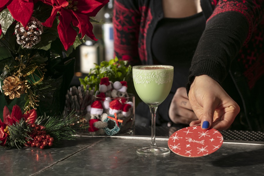A bright green cocktail in an etched Miracle nick-and-nora glass.
