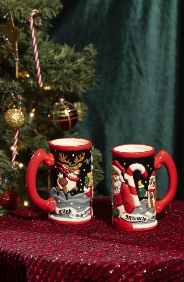 The 2026 Miracle stein, a tall ceramic mug with raised Santa and penguin figures and a red rim.