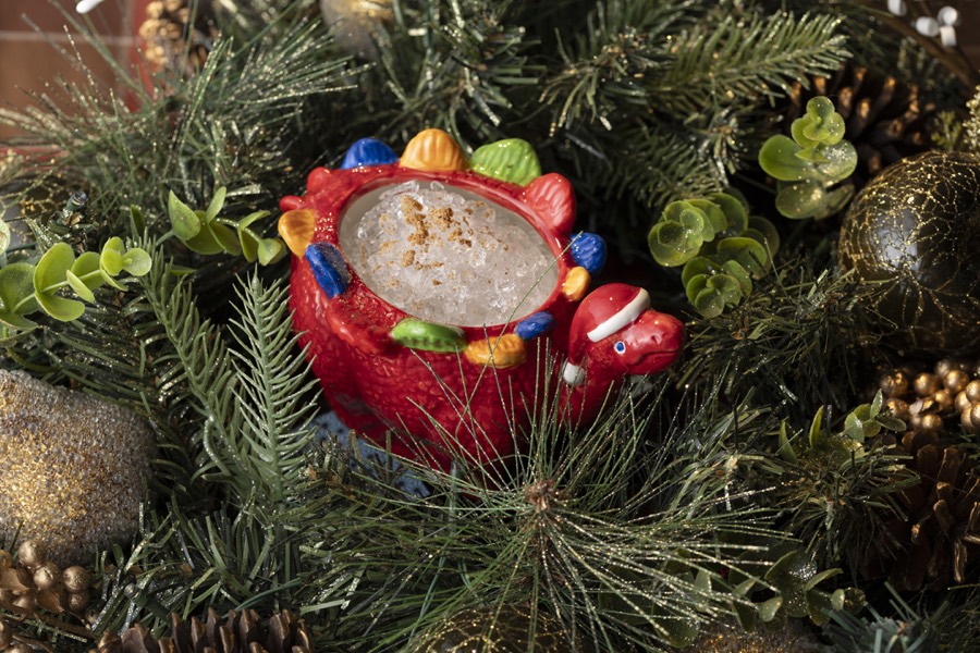 The Sleigh-Saurus mug photographed among ornaments and holly.