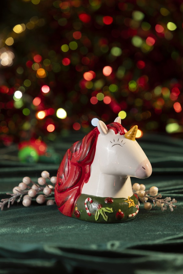 The unicorn mug lit by red and green Christmas bulbs.
