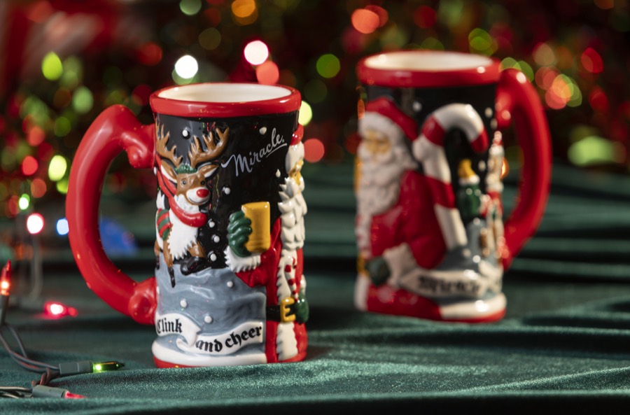 The 2026 Miracle stein: a tall ceramic mug with raised Santa and penguin figures and a red rim.